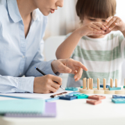 Kids development classes. Little boy playing logical game at psychologist office, unrecognizable specialist making notes